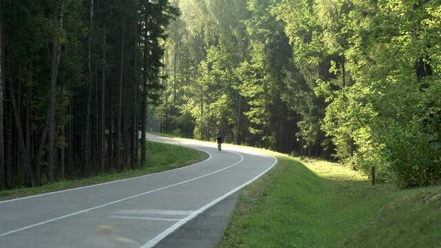 AERIAL DRONE SHOT Tracking, cyclist riding his bicycle on an empty forest road. Shot with DJI Inspire 2