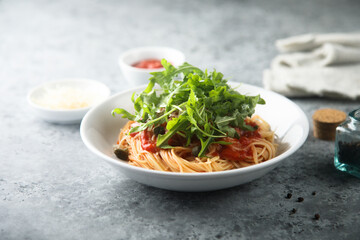 Pasta with tomato sauce, capers and arugula