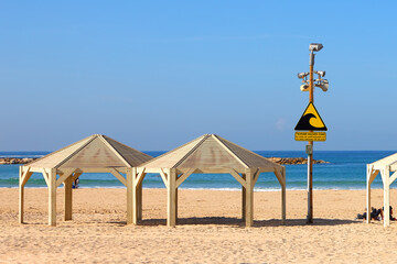 Tsunami warning and evacuation sign located on a beach. The sea and blue sky as background 