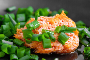 Frozen carrots and green onions in a black pan. Roasters