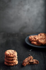 cookies with chocolate shavings on top of a plate on a black background.