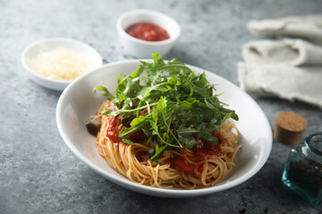 Pasta with tomato sauce, capers and arugula