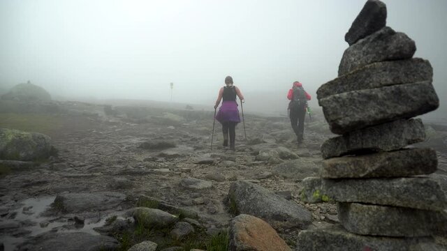 Two girls hiking in Norway at Trolltunga path. Walking in the fog at high attitude.