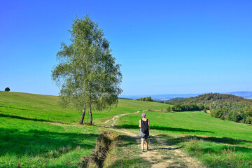Backpacker woman hiking on the country road. Beautiful nature around them. Outdoor activity and walking in the countryside.