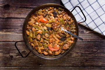 Paella with vegetables on a wooden table, traditional homemade meal