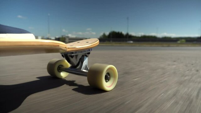 Longboard close up shot from low angle, riding on the asphalt road,