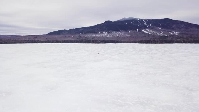 A lone snowmobile treks across the frozen surface of Fitzgerald Pond, Maine.