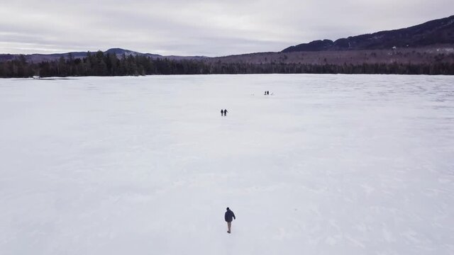 Get an aerial view of Ice Fishing on Fitzgerald Pond, Maine. This is a wide shot circling around the lake.