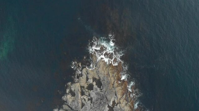 Dramatic aerial top shot of waves crashing onto rocks on a Norwegian Island