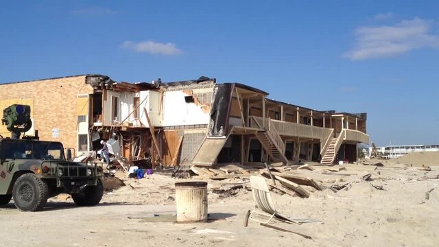 After Hurricane Sandy a military vehicle stands in front of destroyed buildings with sand everywhere.