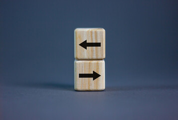 Conceptual image of choice and direction. Wooden cubes with arrows pointing in opposite directions. Beautiful grey background, copy space.