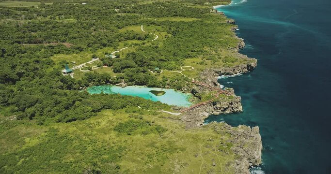 Emerald water lake at green tropic forest of landmark Weekuri at Sumba Island, Indonesia. Limpid loch with greenery tropical plants at birds-eye drone shot. Asian attraction aerial view