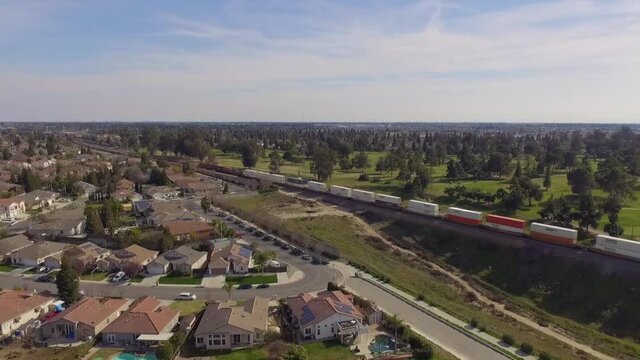 Aerial of freight train travelling alongside a residential neighborhood in Fresno, California.