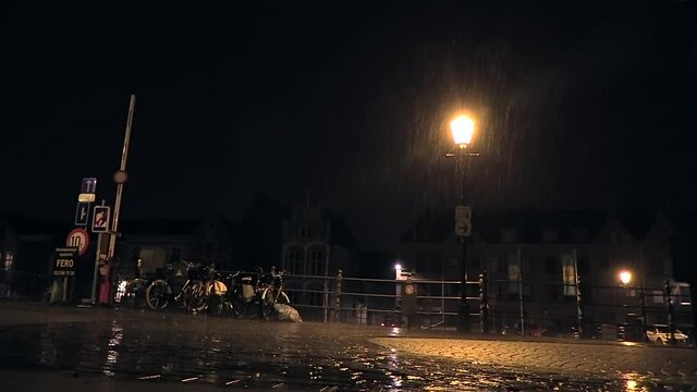 car passing over a bridge when lightning strikes with pouring rain at night in the city of Mechelen, Belgium