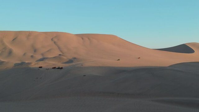 Sunset Aerial Drone Footage Above Sand Dunes Of Peru. Close To Ica And Huacachina. People Walking And Sand Boarding. Oasis Nearby. Dune Buggy Driving Up The Sand Dunes.