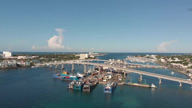 4K Cinematic Aerial flyover of boats and barges toward paradise island bridge.