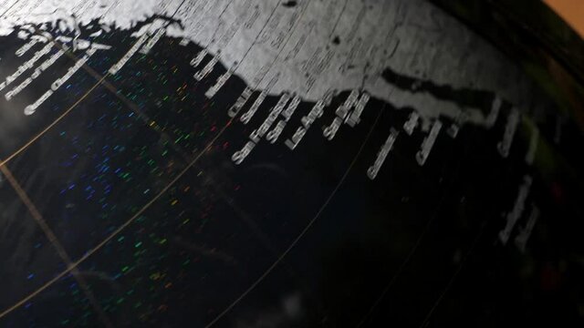 Close up shot of a spinning black and metallic globe the stops on europe and north africa. Slow motion