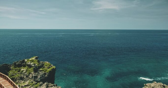 Closeup aerial view of bridge at limpid lake on green cliff ocean shore. Picturesque Indonesian landscape of Weekuri loch, Sumba Island with greenery tropical plants. Cinematic drone shot