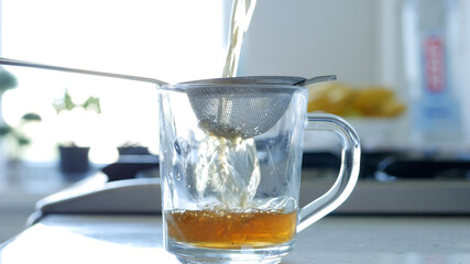Image with Making a Hot and Aromatic Tea Using a Strainer and Natural Tea Leaves