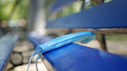 Used Medical Face Mask Abandoned on a Bench in the Park, Dangerous Garbage