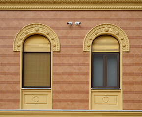 Two windows with opened and closed shutters on the renovated yellow building