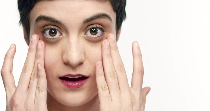 Close up of a woman looking into camera dapping under her eyes.