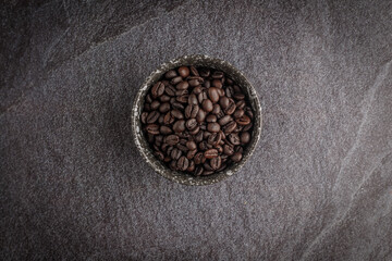 Coffee cup with roasted beans on stone background. Top view with copy space