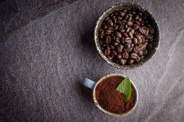Naklejka premium Coffee cup with roasted beans on stone background. Top view with copy space