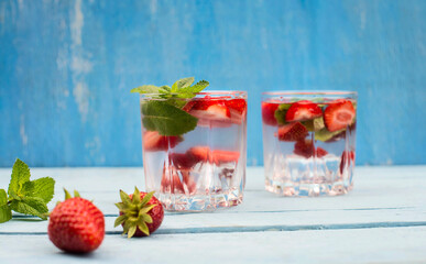 Refreshing summer drink with strawberry and mint  in glasses on blue shabby vintage wooden table.