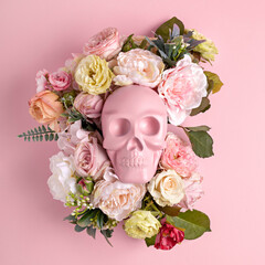 Creative Halloween layout made with pink skull surrounded by flowers on pink background. Minimal scary concept. Flat lay.