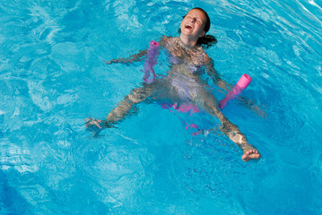 Young girl having fun and laughing while swimming in a pool