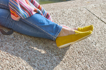 woman legs in yellow moccasins against the background of a concrete wall