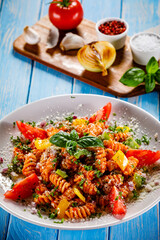 Fusilli with tomato sauce, meat and parmesan on wooden table
