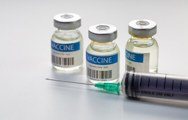 Injection syringe with vaccine bottles on white background