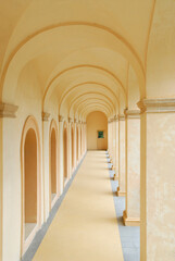 Hallway with arches at La Rocca Spoleto leading to a window of green