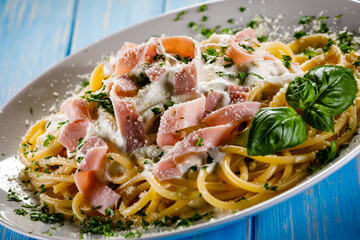 Pasta carbonara on white plate on wooden table
