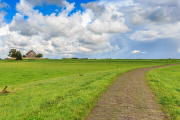 Landscape former Zuiderzee Island Schokland in the Dutch Noordoostpolder  created by the drying of the IJsselmeer  with stone road to old House against sky with scattered clouds
