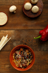 Udon with chicken and mushrooms in Thai sauce on a wooden table copy space