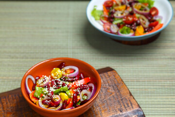 Two Plates with Pan-Asian salad with sesame seeds and tamarind on wooden stands.
