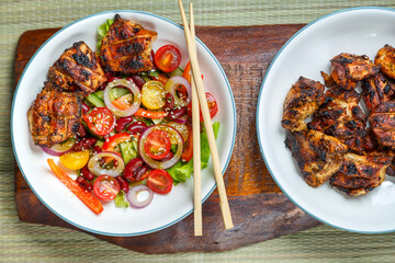 Plates of Pan-Asian sesame and tamarind salad and grilled chicken pieces in pad thai sauce.