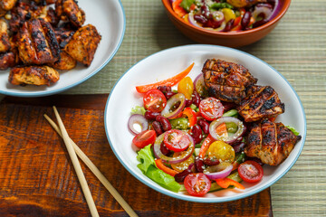 Plates of Pan-Asian sesame salad and grilled chicken pieces in terriyaki sauce.