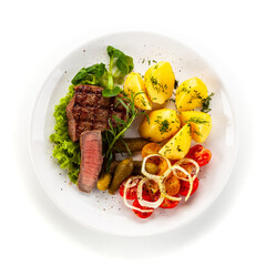 Barbecue beef steak with boiled potatoes and fresh vegetables on white background
