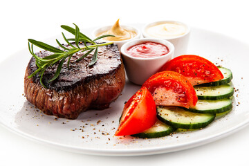 Barbecue beef steak with fresh tomatoes and cucumbers, mustard, mayonnaise and ketchup on white background
