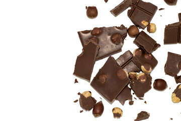 Pieces of black and milk chocolate with whole hazelnuts, on a white background, close up