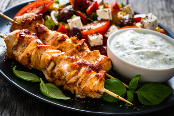 Fried souvlaki, greek salad and tzatziki on wooden table