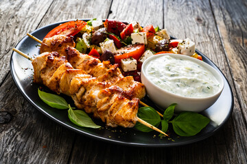 Fried souvlaki, greek salad and tzatziki on wooden table