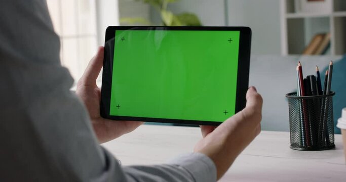 Close up shot of hands holding a tablet computer with green mock up screen. A template for video conference or online store 4k footage