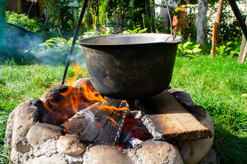 Metal cauldron saucepan in soot for cooking on a campfire hanging over a campfire