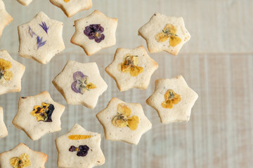 Star shaped biscuits decorated with edible flowers, pansies and cornflower petals. 