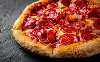 Pepperoni Pizza with Mozzarella cheese, salami, Tomato sauce, pepper, Spices. Italian pizza on Dark grey black slate background